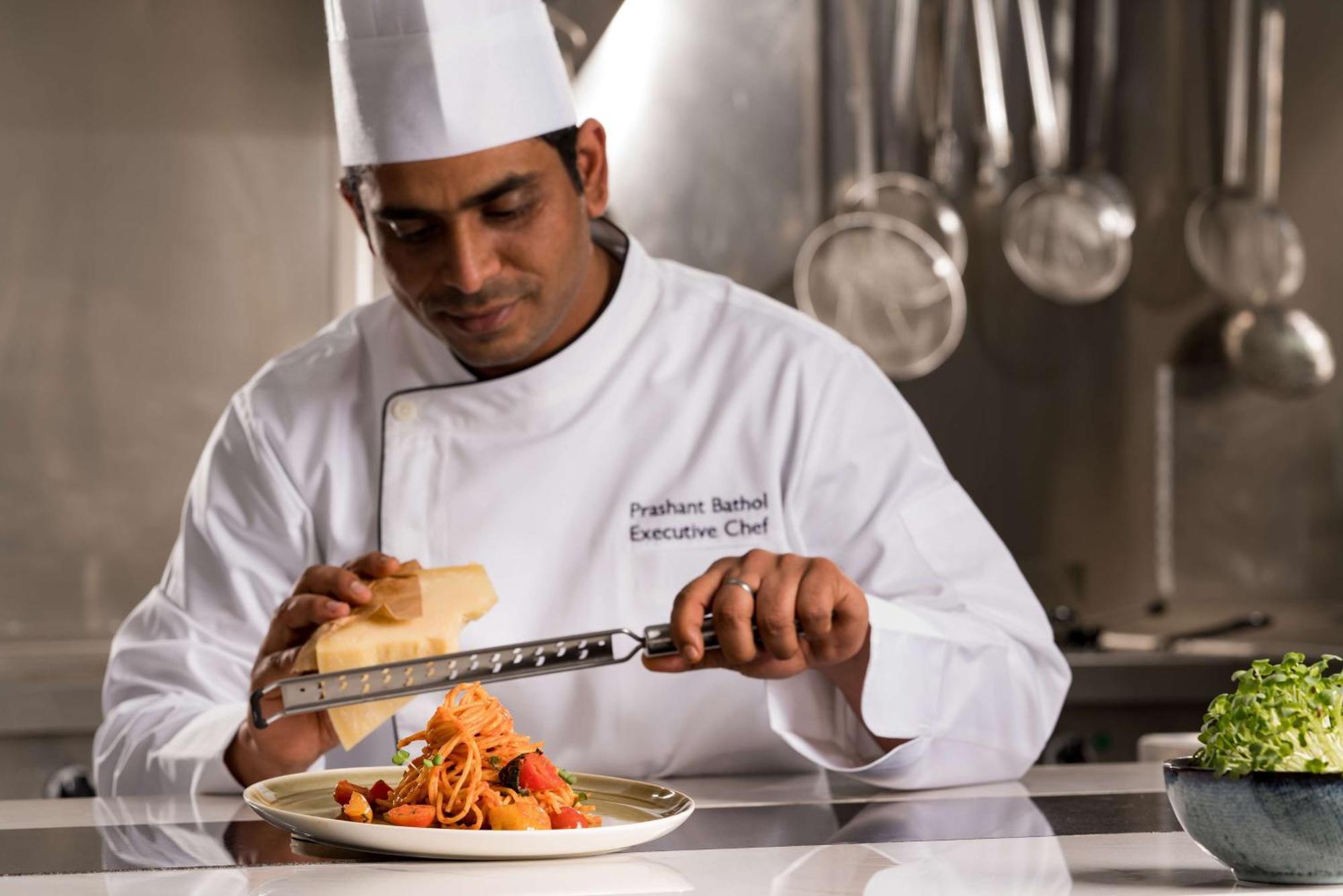 Radisson Blu Hotel Riyadh Qurtuba Exterior foto A chef grating cheese over a pasta dish